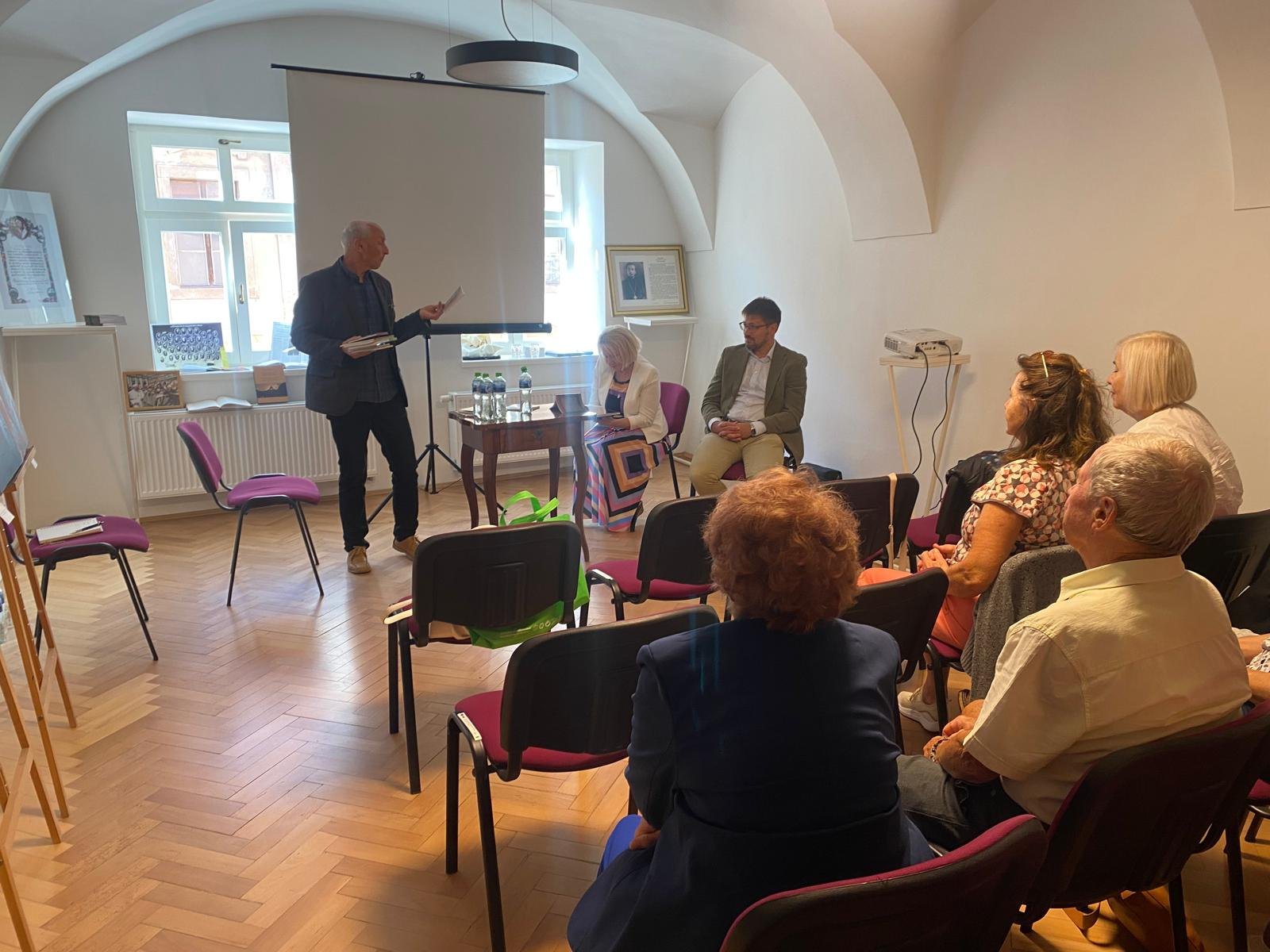 Anton Lauček prednáša, za stolom Žofia Bendžalová Kellnerová a Martin Lukačišin